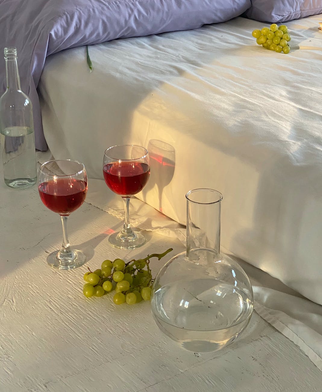 glasses with wine near jar with water and bed