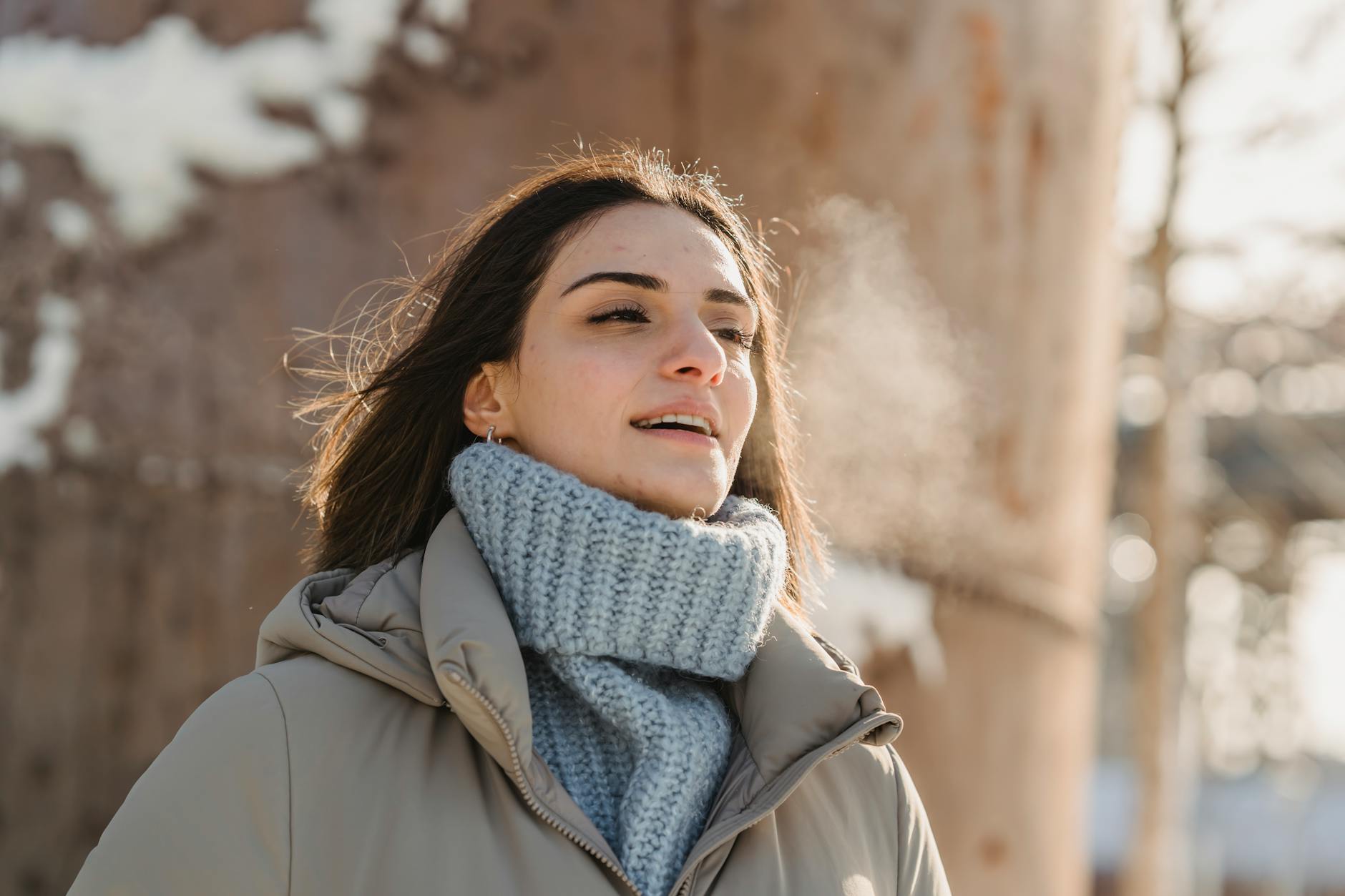 young woman exhaling steam on freezing cold weather