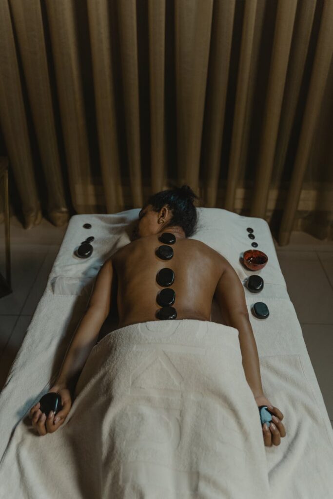 a woman with peebles on her back lying on white bed