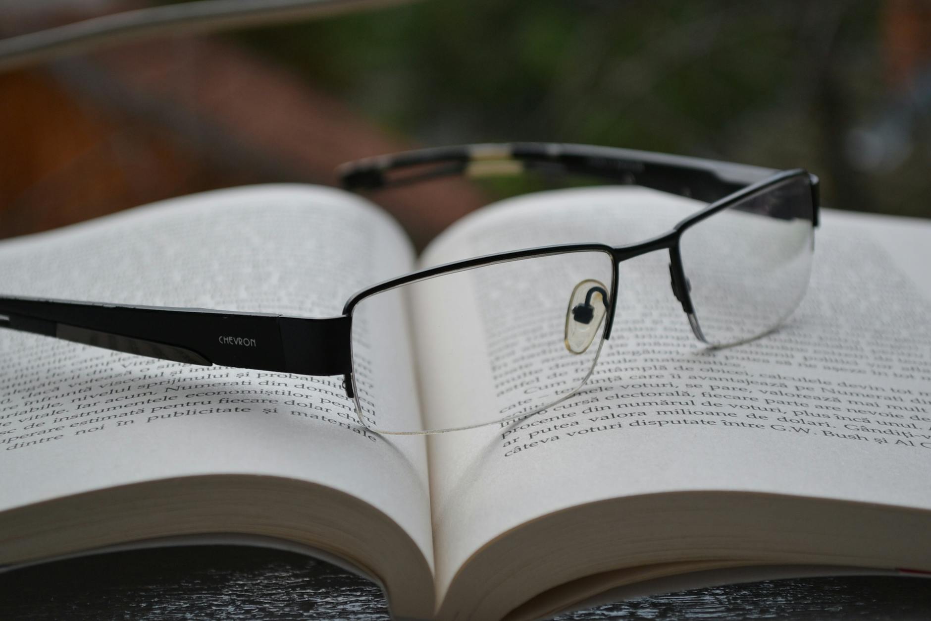 clear eyeglasses with black frames on opened book